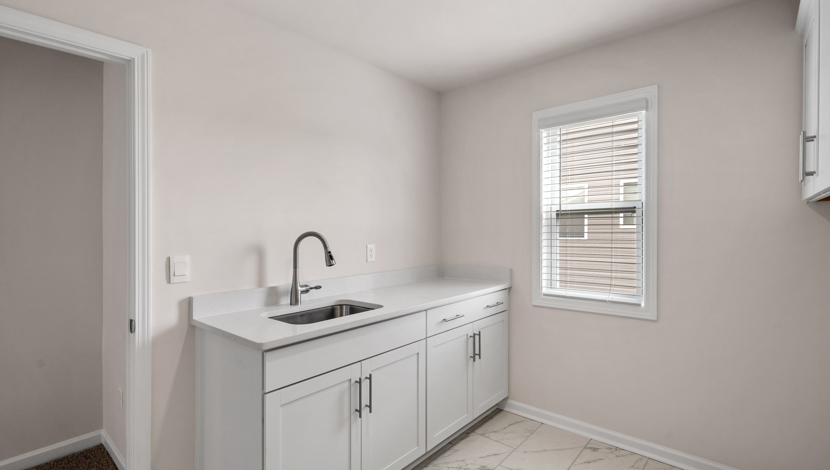 Walk-in laundry room with sink cabinet and storage cabinets.