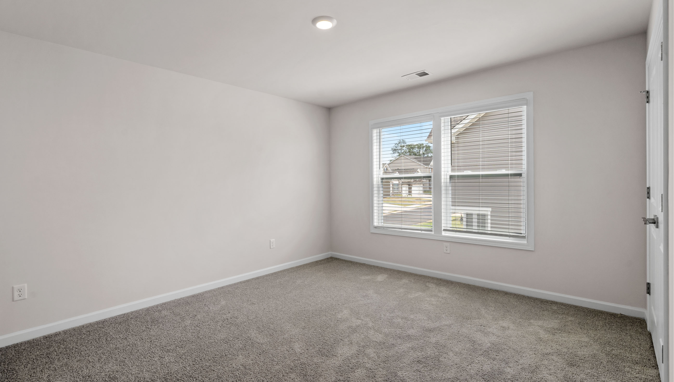 Bedroom with two large windows and carpet.