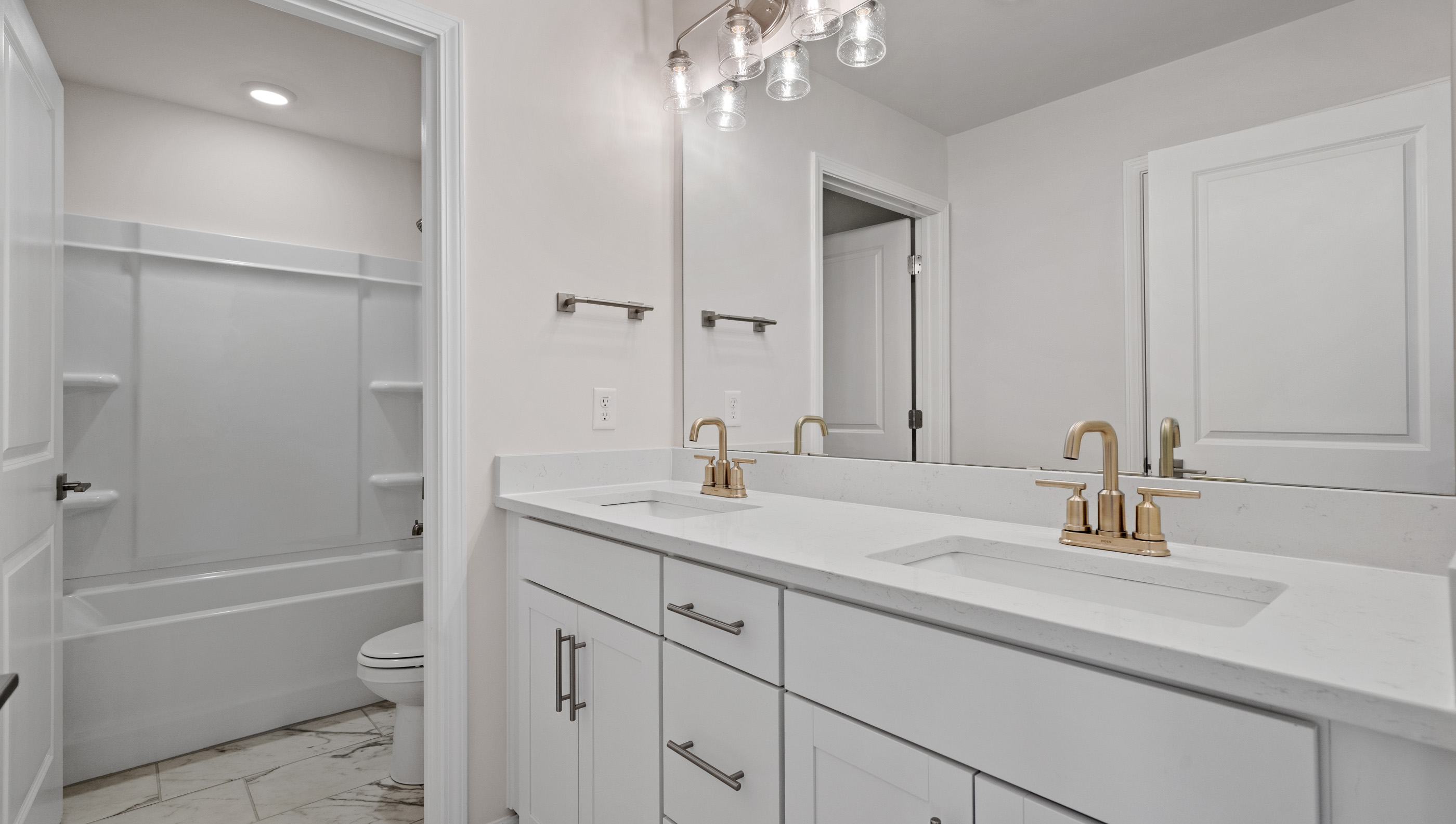 Hall bathroom with dual sink vanity and combination shower / tub.