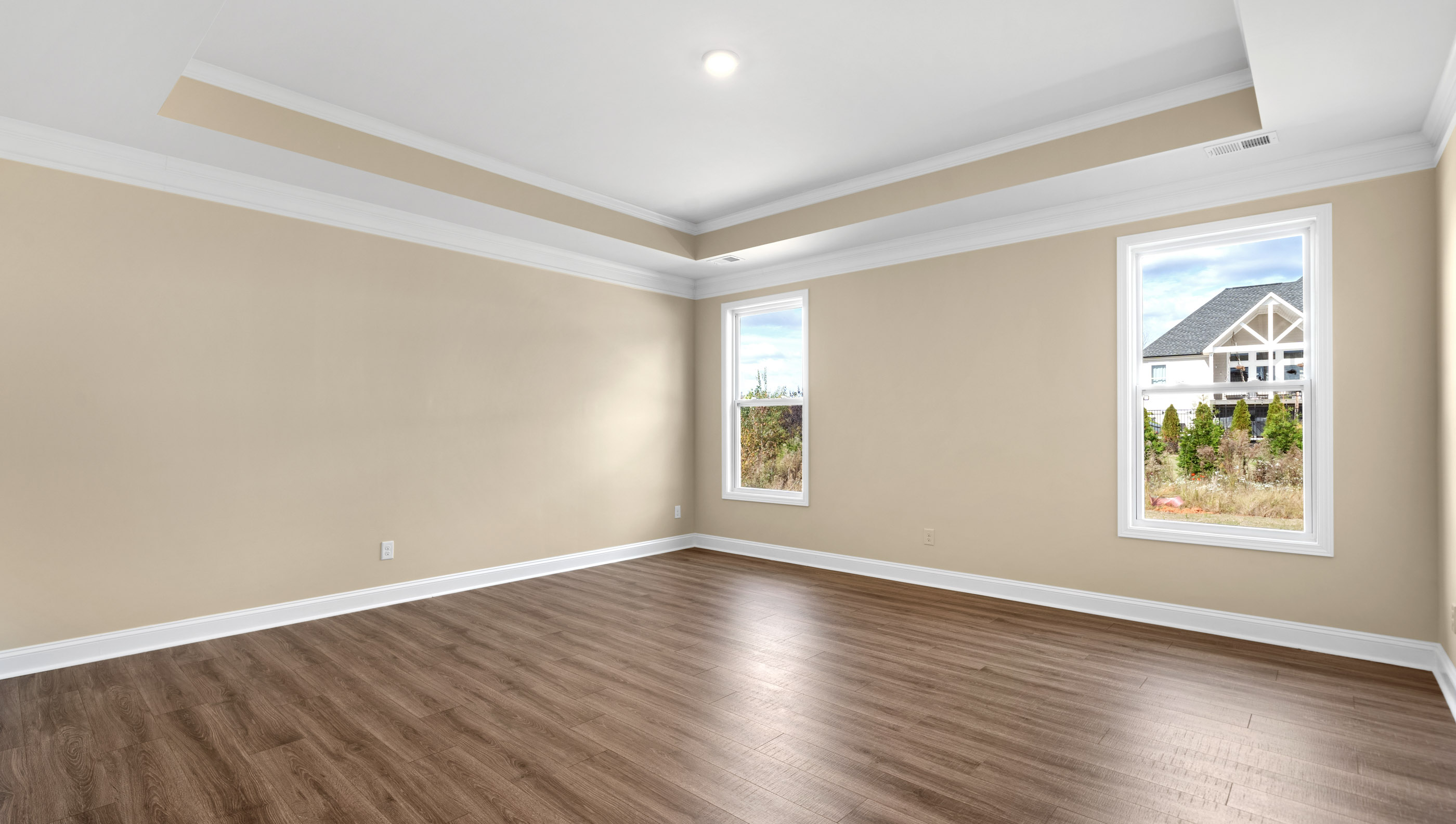 Primary bedroom on the main level with trey ceiling and large windows.