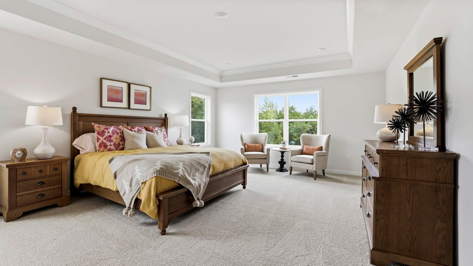 Primary bedroom with carpet and windows.