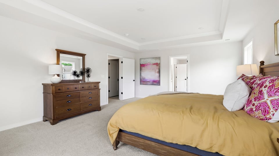 Primary bedroom with carpet and windows.