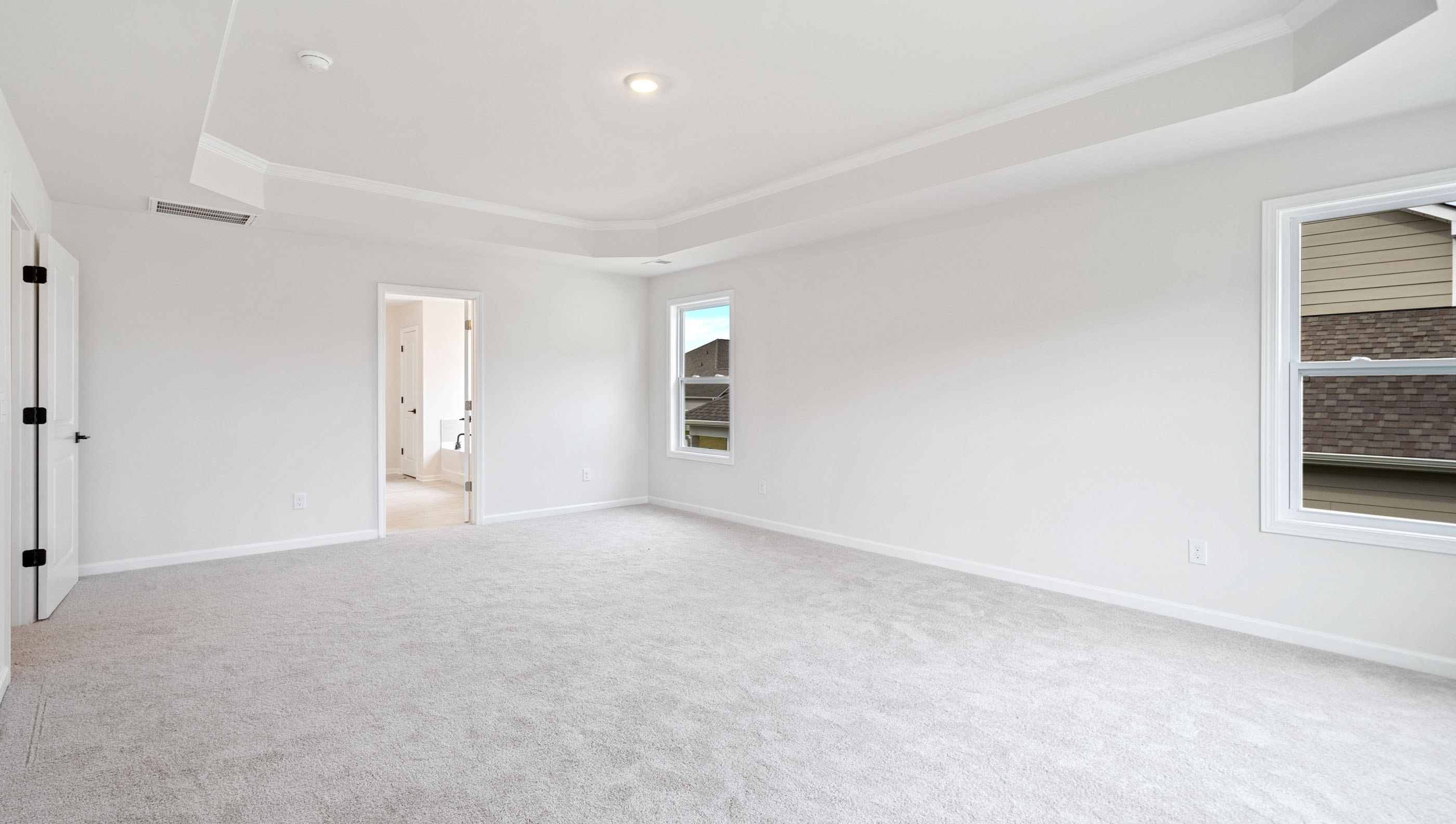 Primary bedroom with trey ceiling and several windows.