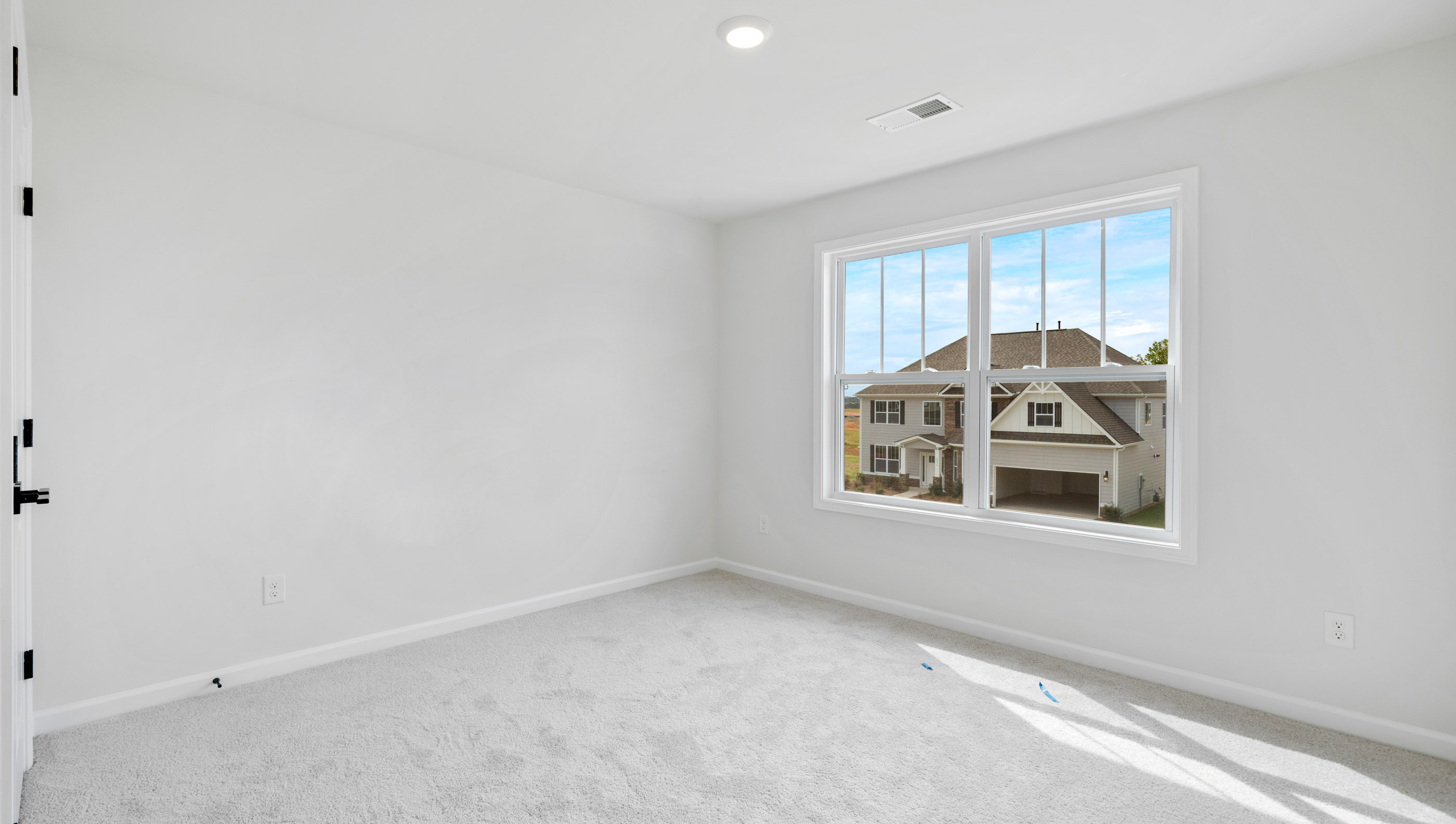 Bedroom with large window and carpet.