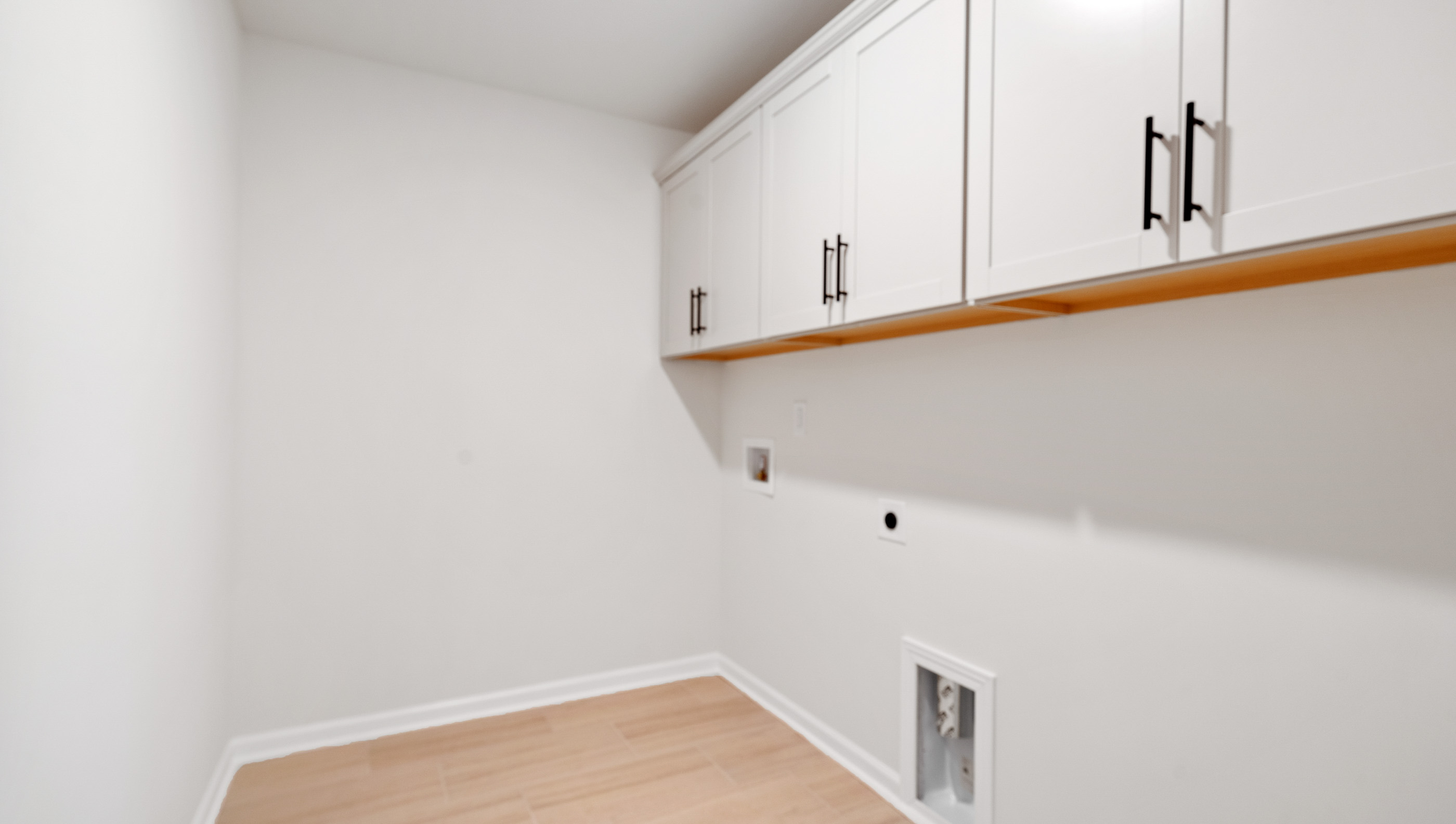 Walk-in laundry room with cabinets.