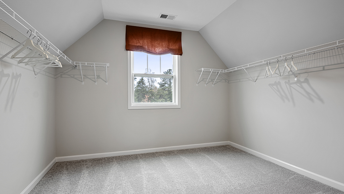 Primary closet with carpet and window.