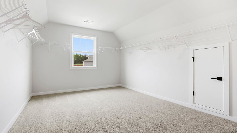 Primary closet with carpet and window.