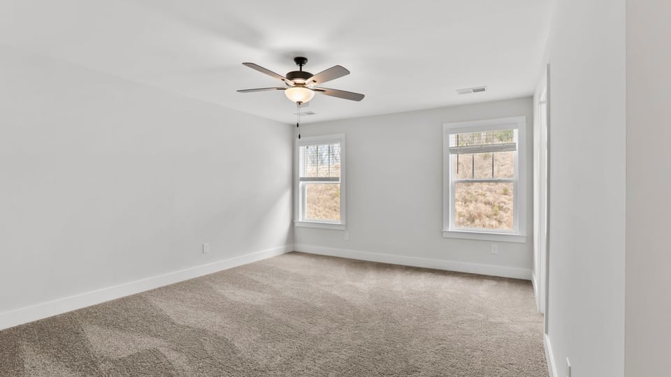 Primary bedroom with carpet and windows.