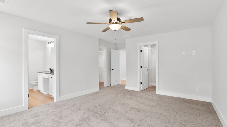 Primary bedroom with carpet and windows.