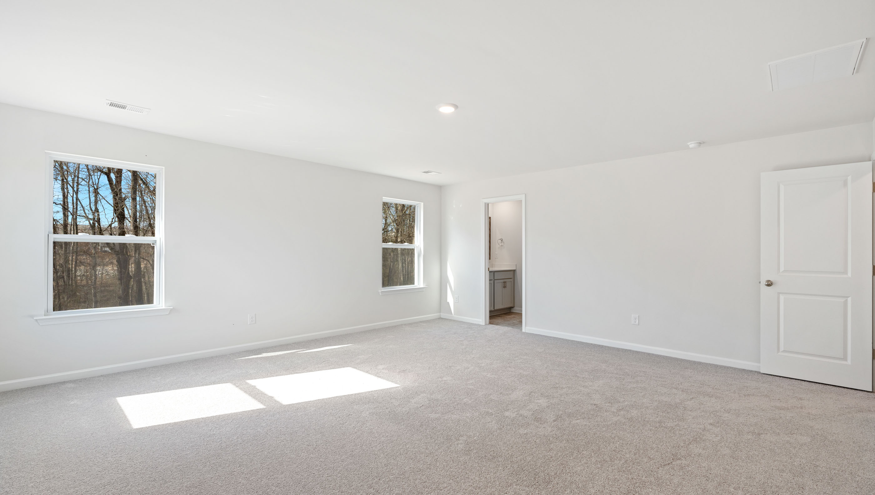 Primary bedroom with carpet and window.