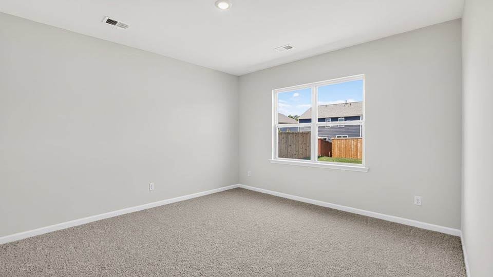 Primary bedroom with carpet and windows.
