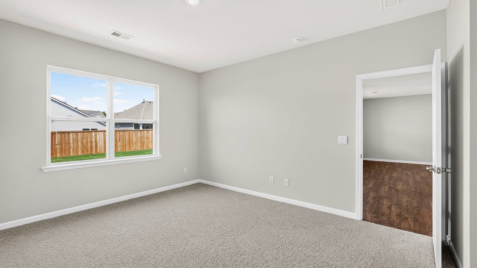 Primary bedroom with carpet and windows.