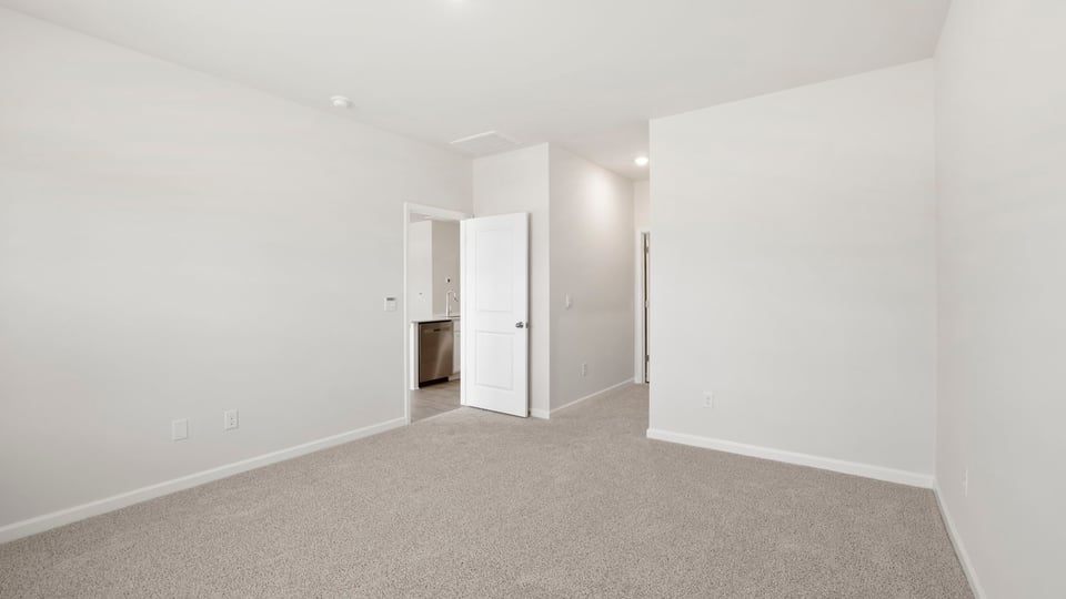 Primary bedroom with carpet and windows.