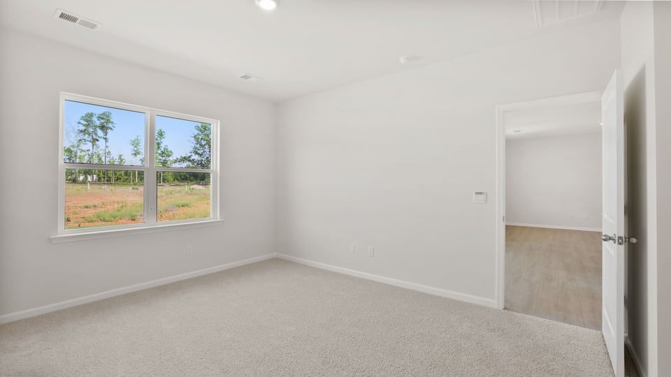 Primary bedroom with carpet and windows.