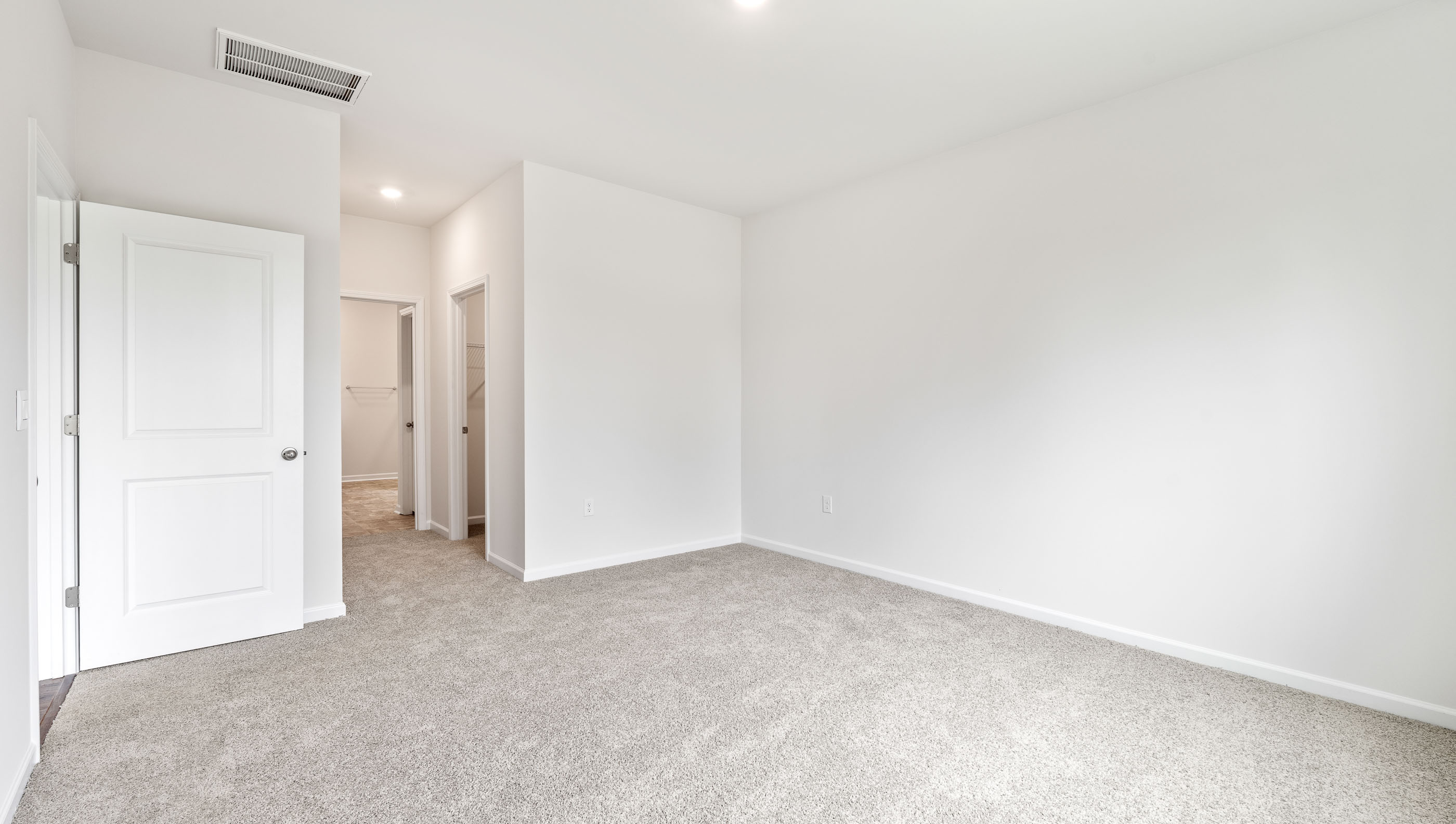 Primary bedroom with large window and carpet.