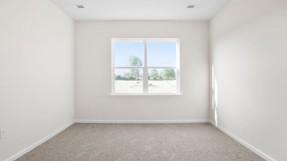Primary bedroom with carpet and window.