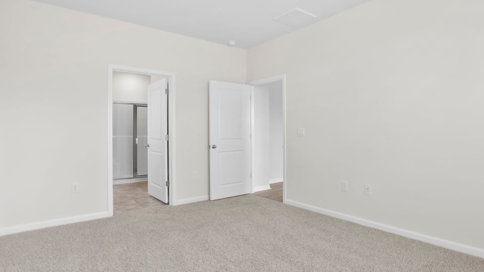 Primary bedroom with carpet and window.