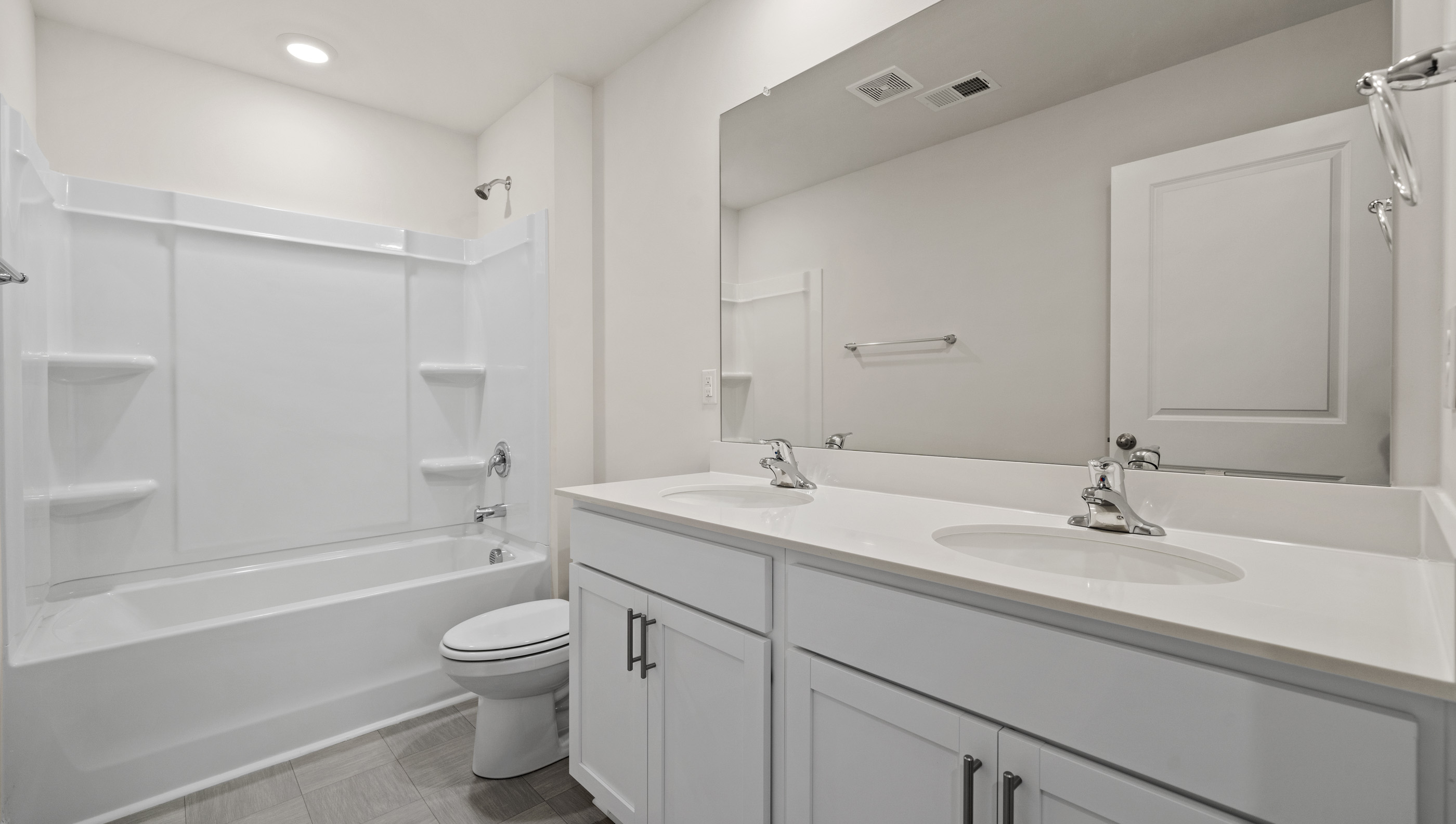 Hall bathroom with dual sink vanity and combination shower / tub.