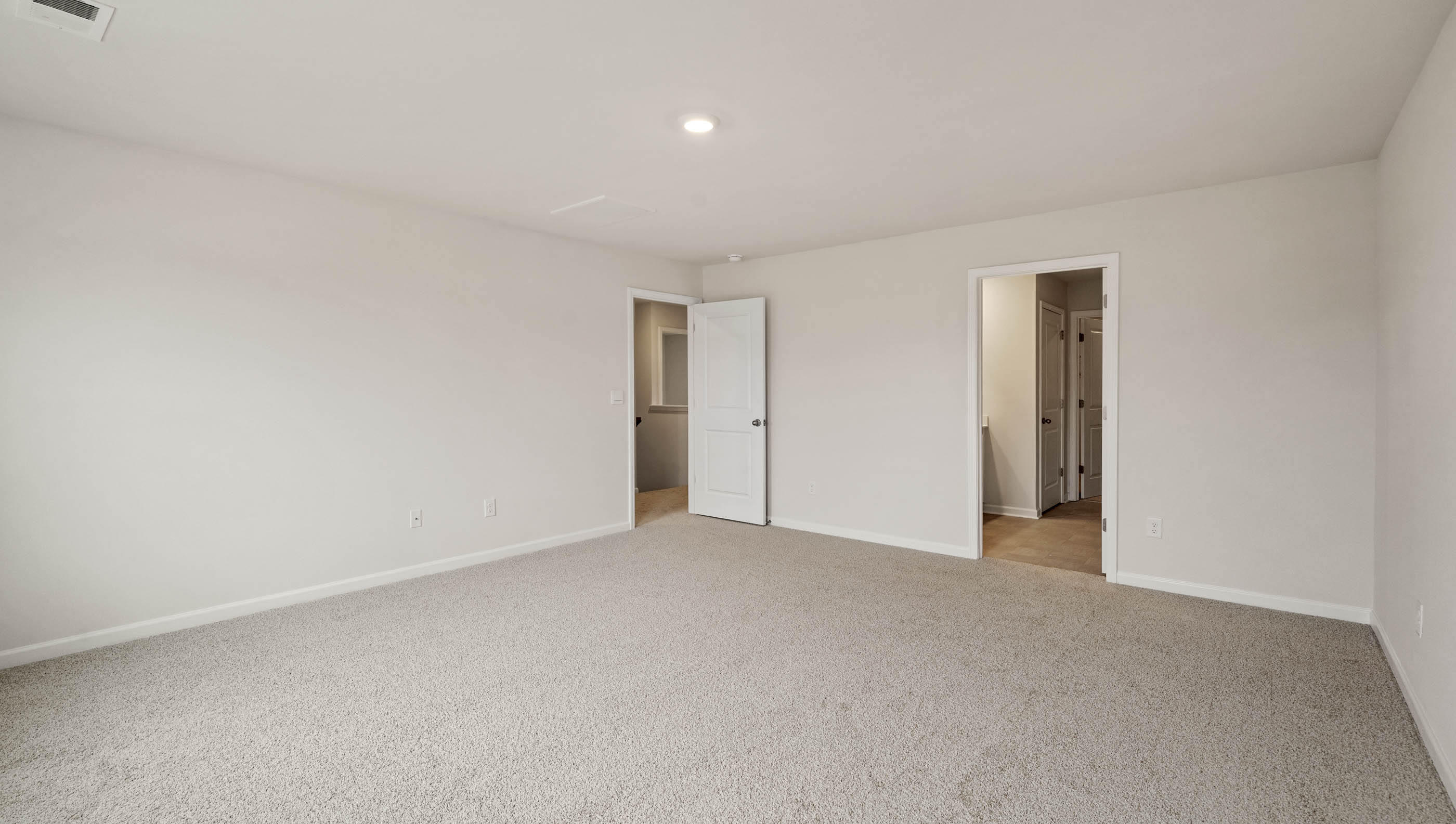 Primary bedroom with two large windows and carpet.