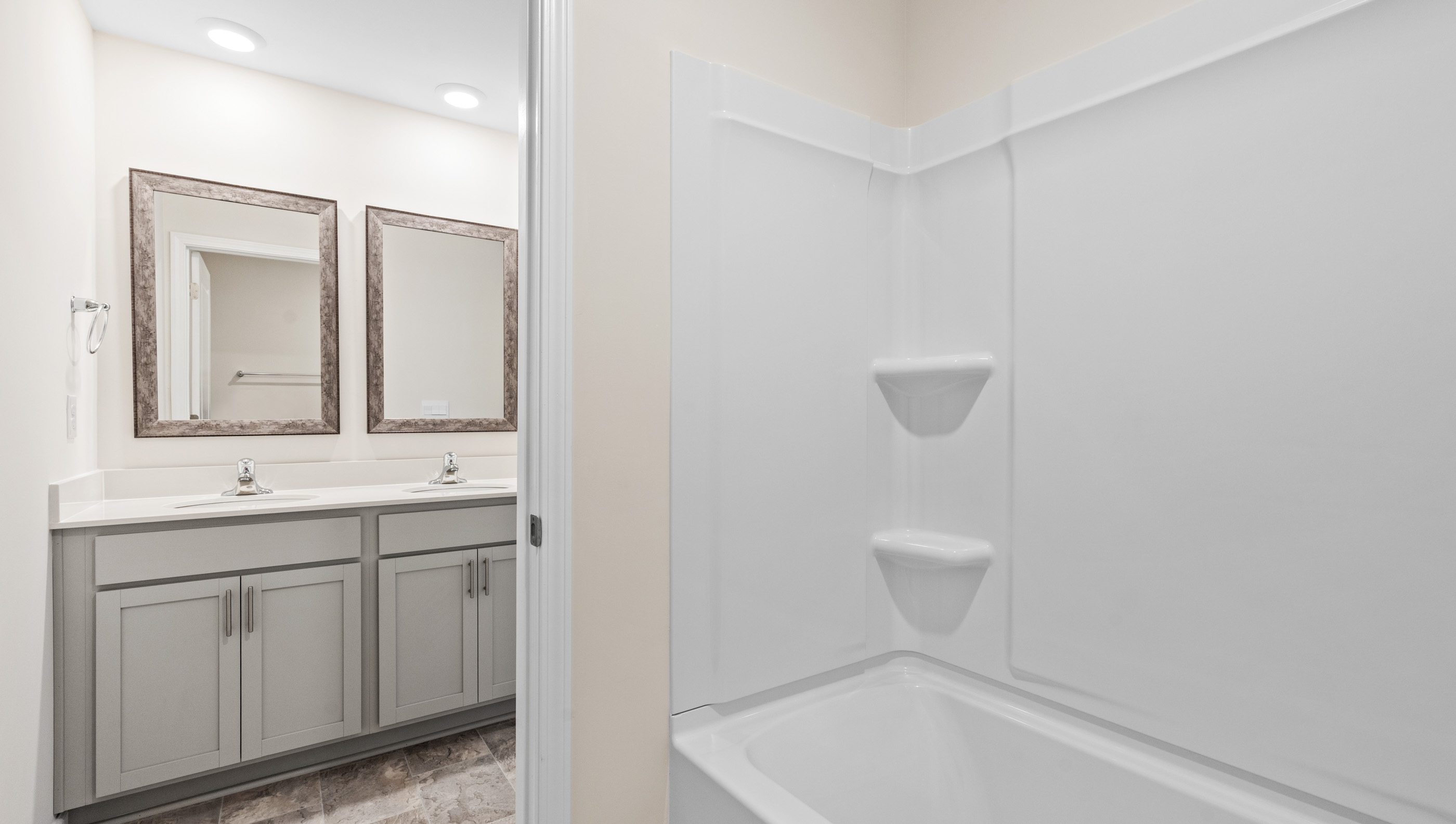 Hall bathroom with dual sink vanity and combination shower / tub.