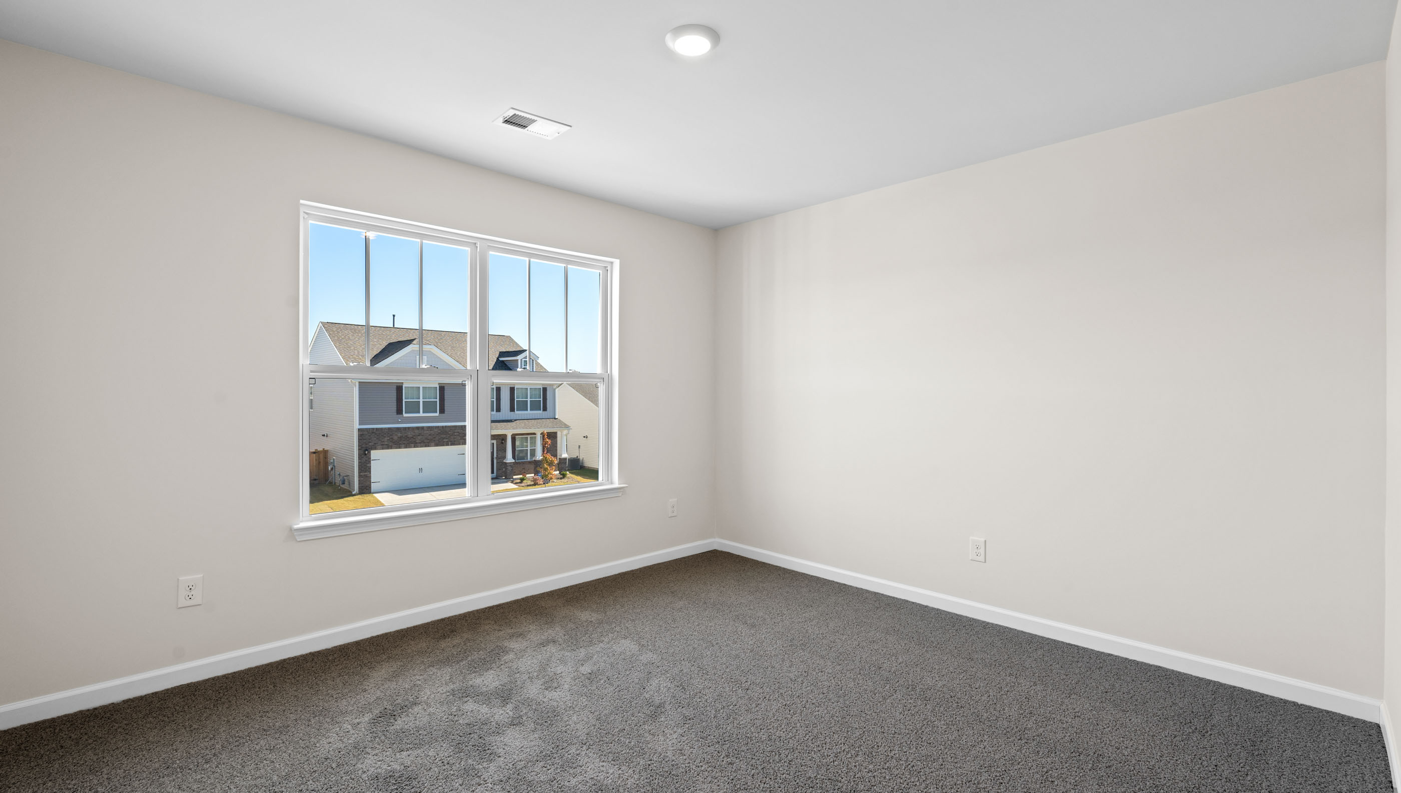 Primary bedroom with large window and carpet.