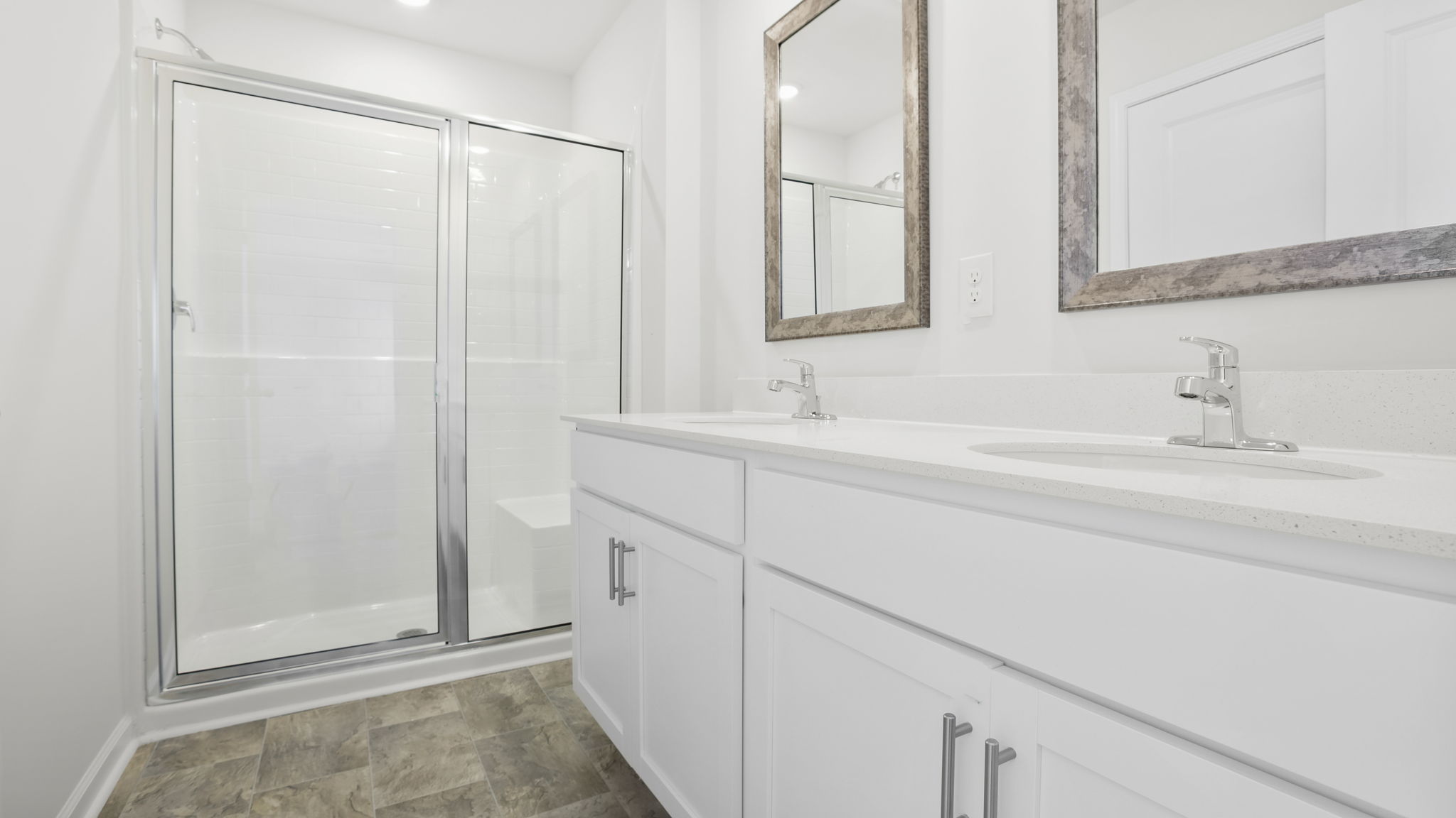 Bathroom with double vanity sink and walk in shower.