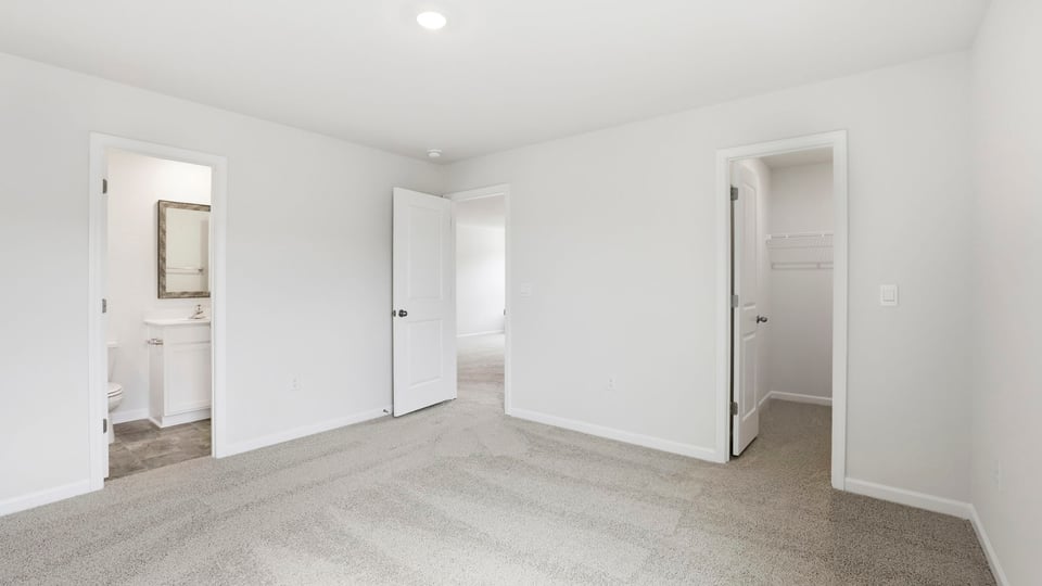 Primary bedroom with carpet and windows.