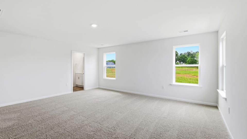 Primary bedroom with carpet and windows.