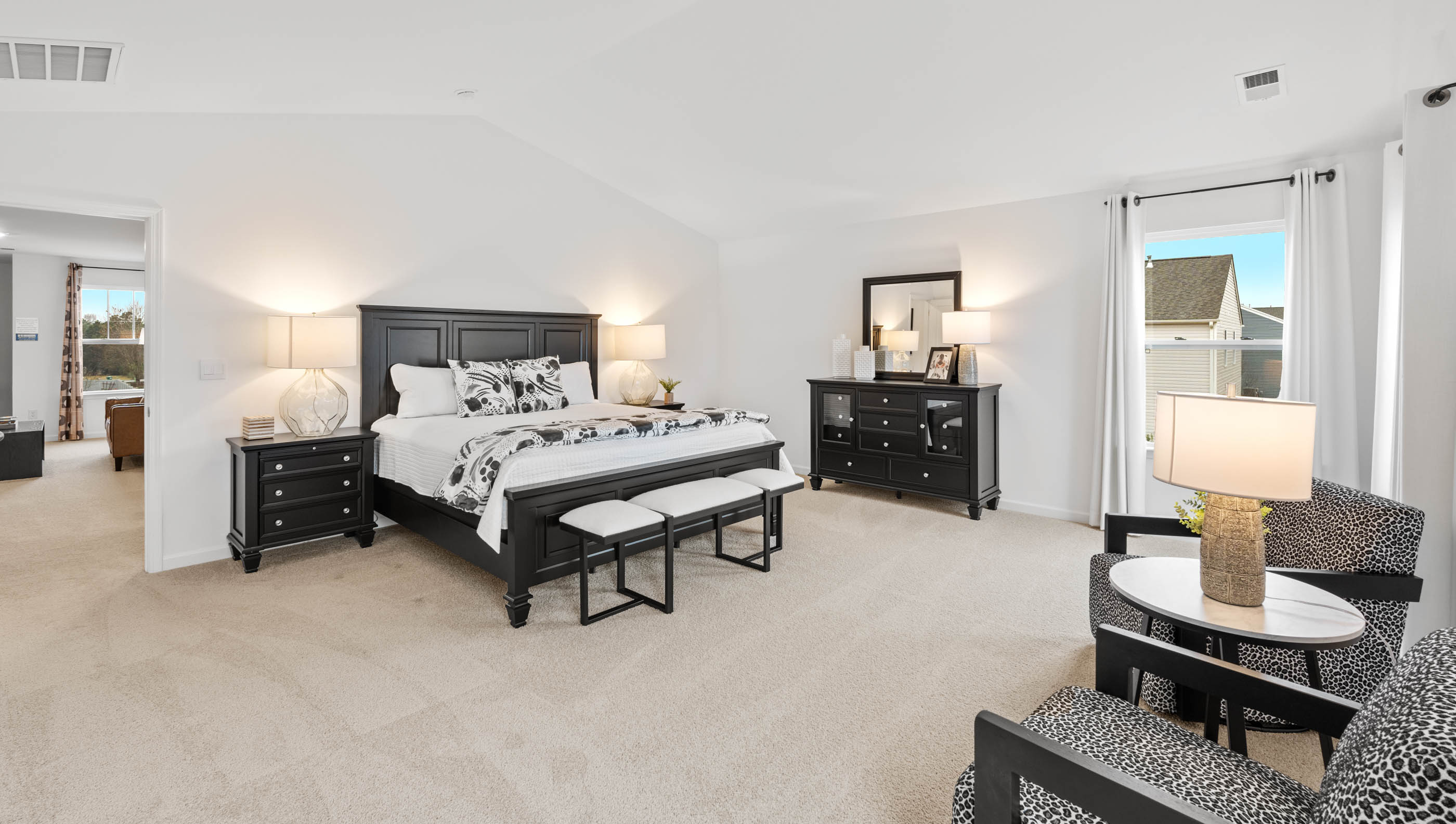 Primary bedroom with carpet and windows.