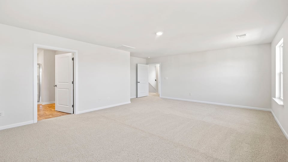 Primary bedroom with carpet and windows.