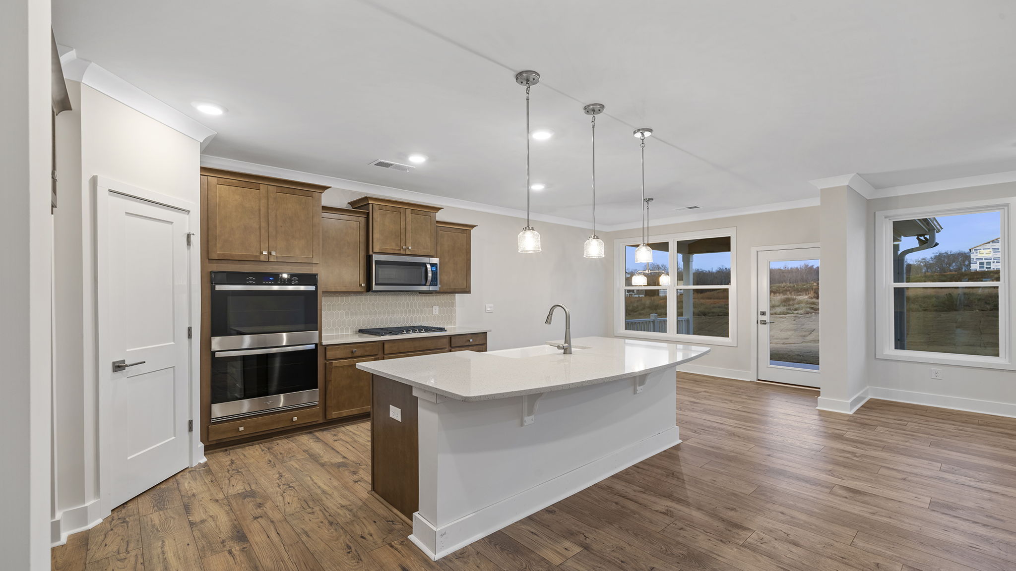 Kitchen with island and quartz countertops and pendulum lighting.
