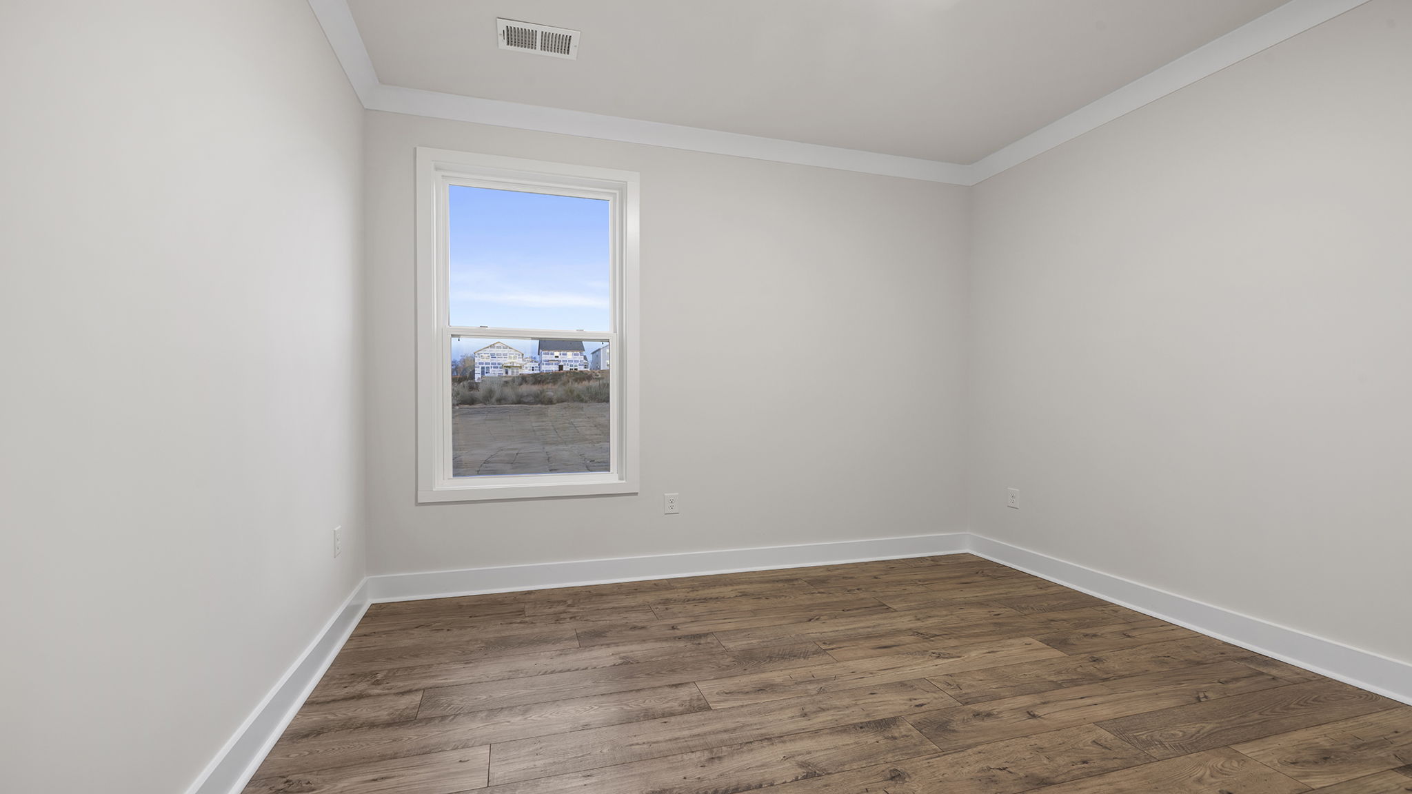 Bedroom on the main level with window and laminate flooring.