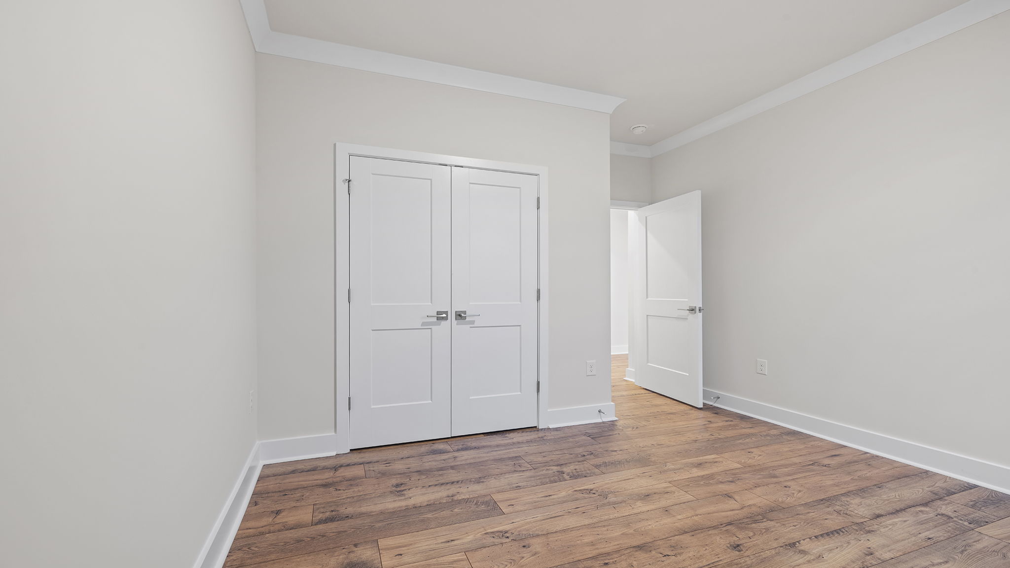 Bedroom on the main level with window and laminate flooring.