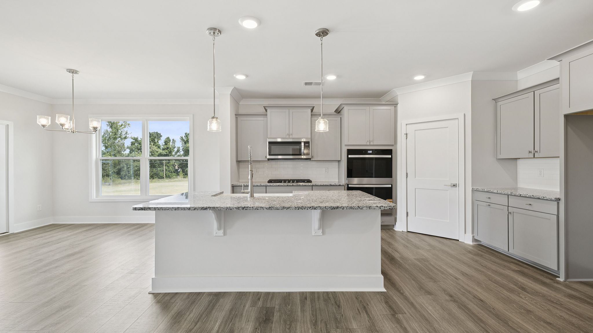 Gourmet kitchen with island, pendulum lighting and quartz countertops.