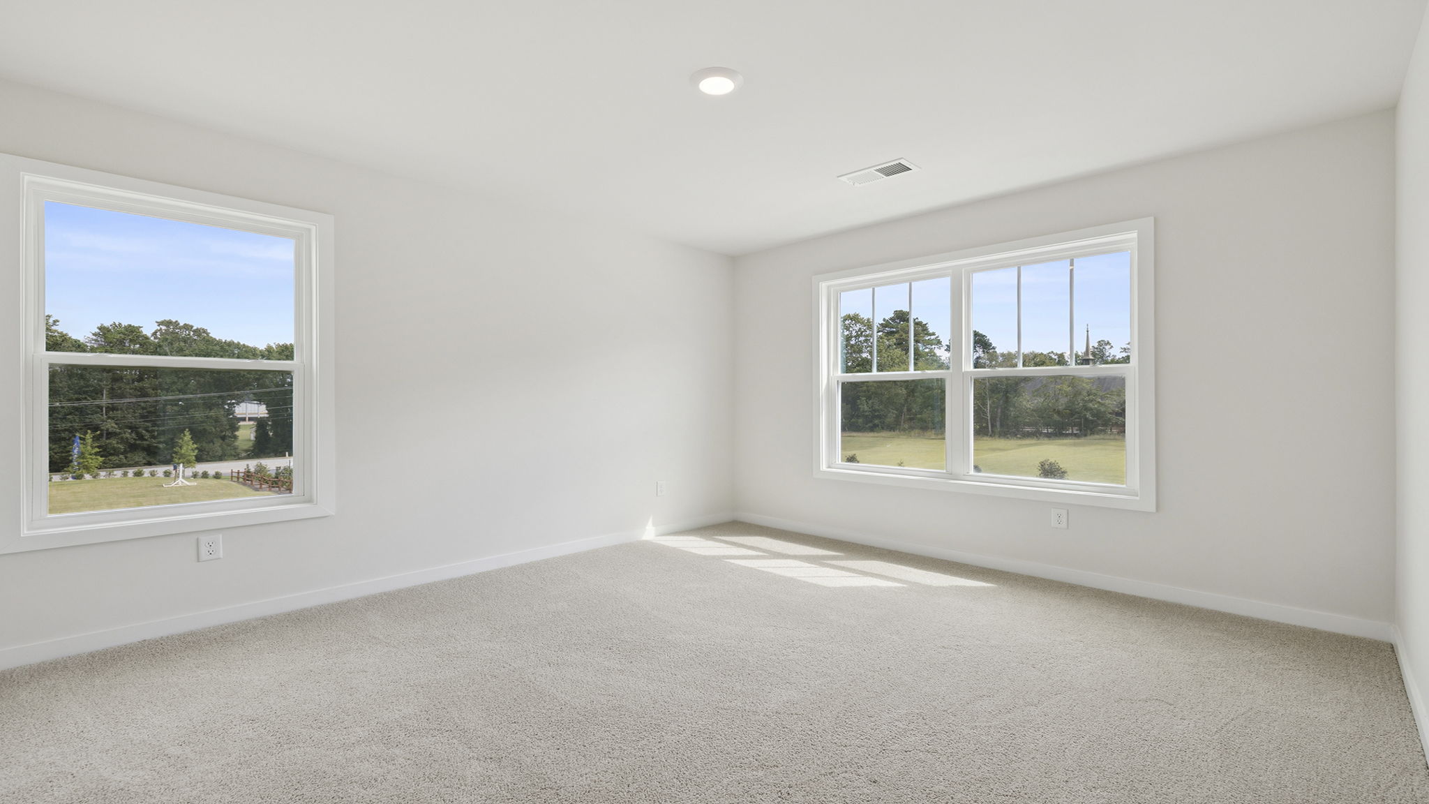 Bedroom with two large windows and carpet.