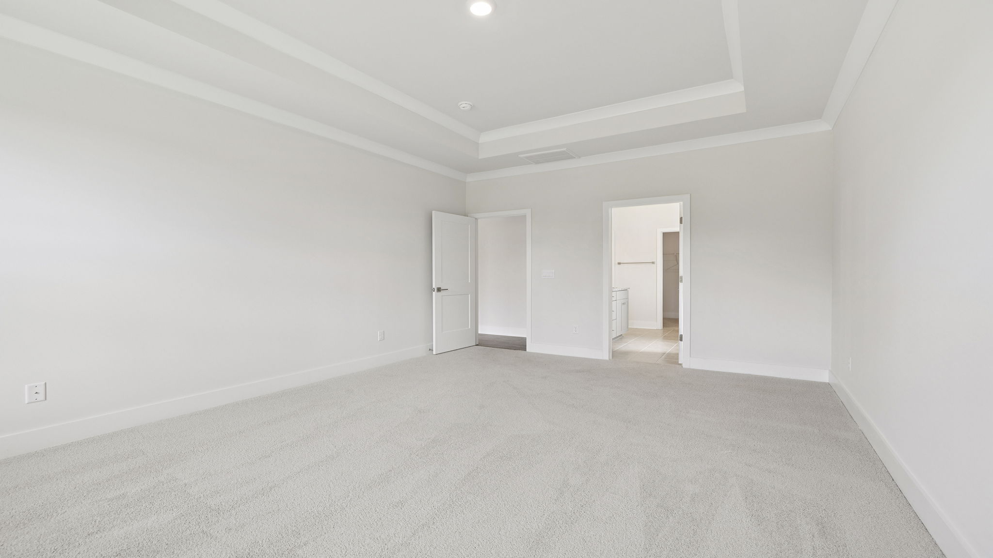 Primary bedroom on the main level with two large windows, trey ceiling and recessed lighting.