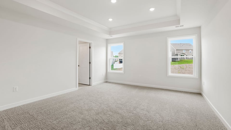 Primary bedroom with carpet and windows.