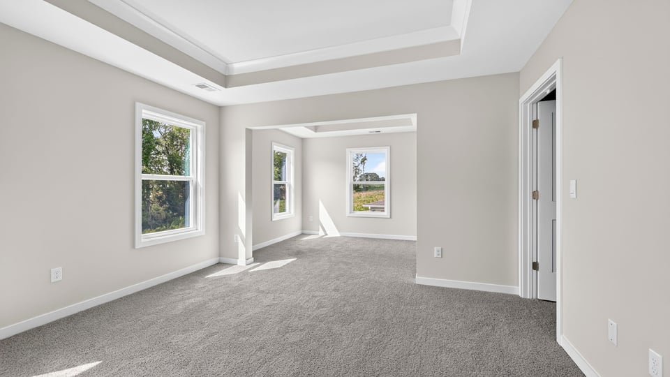 Primary bedroom with carpet and windows.
