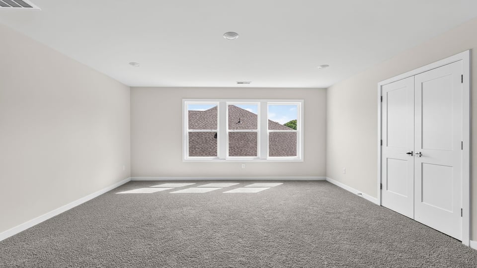 Primary bedroom with carpet and windows.