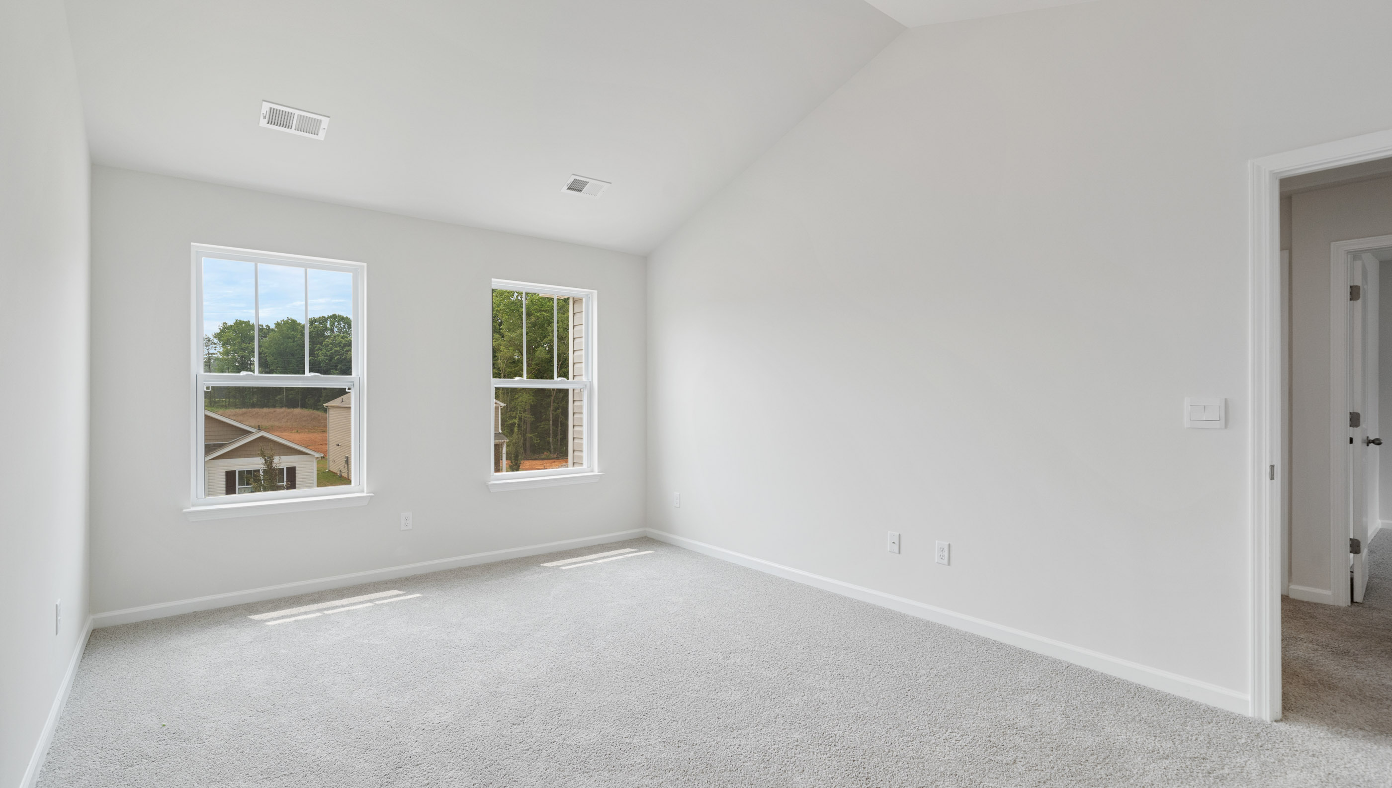 Primary bedroom with carpet and windows.