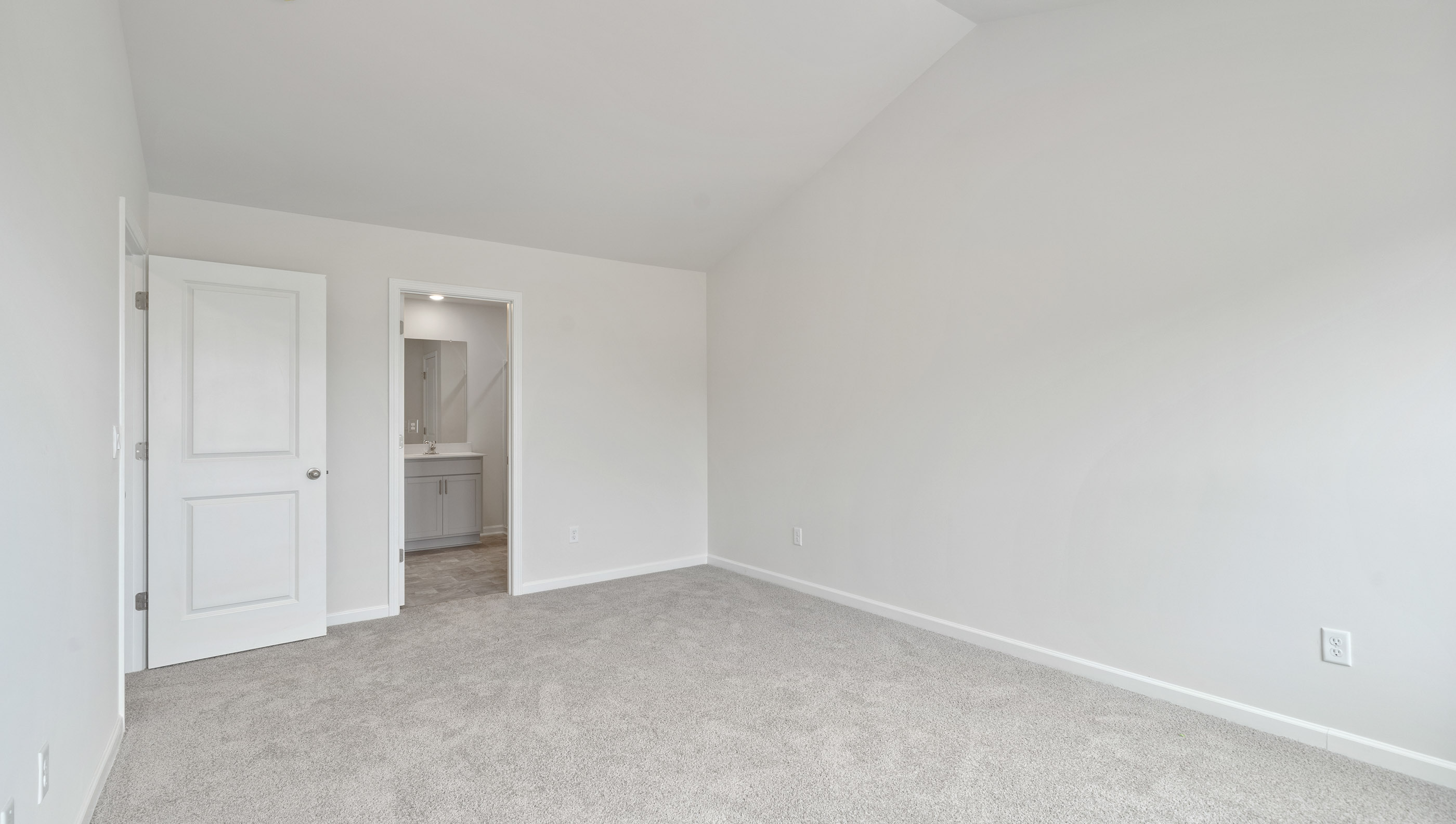 Primary bedroom with carpet and windows.