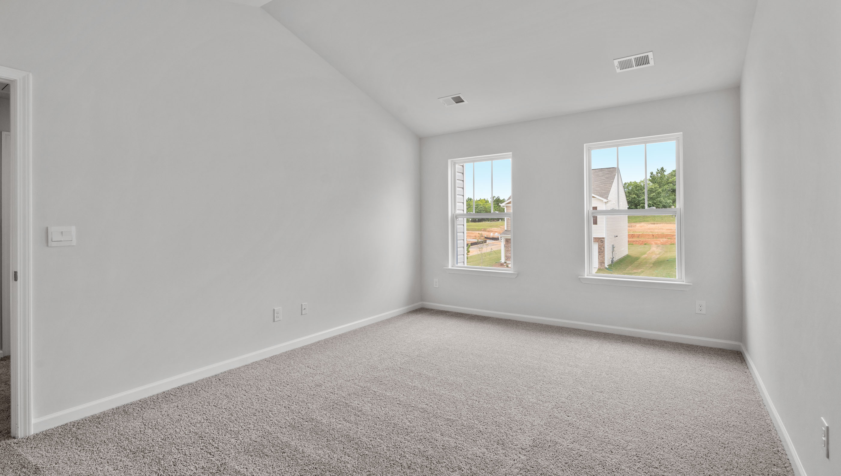 Primary bedroom with carpet and window.