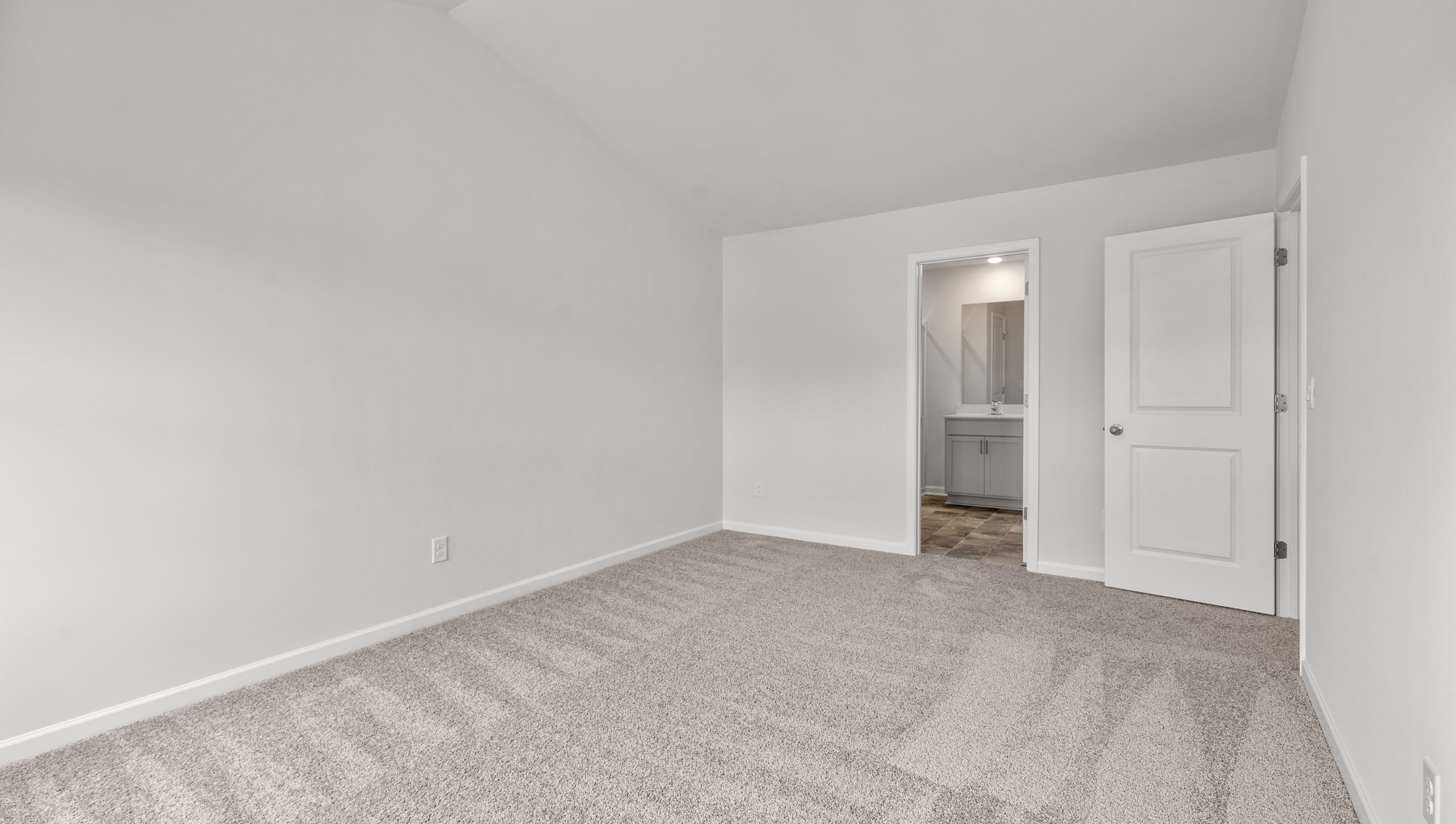 Primary bedroom with carpet and window.