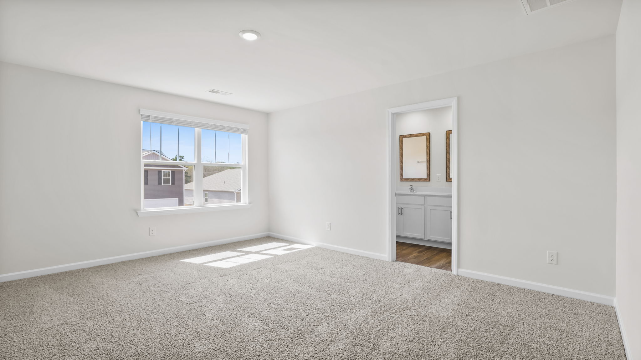 View of primary bedroom with large window and entrance into primary bath.