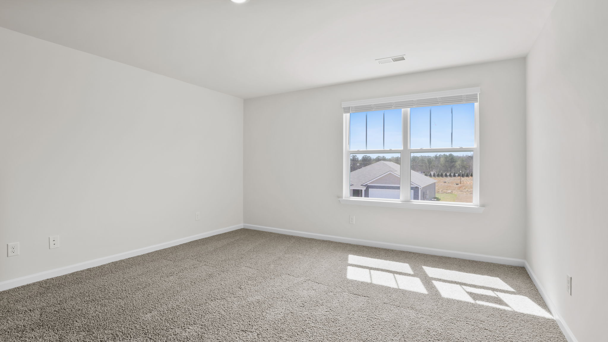 Primary bedroom with large window and carpet.