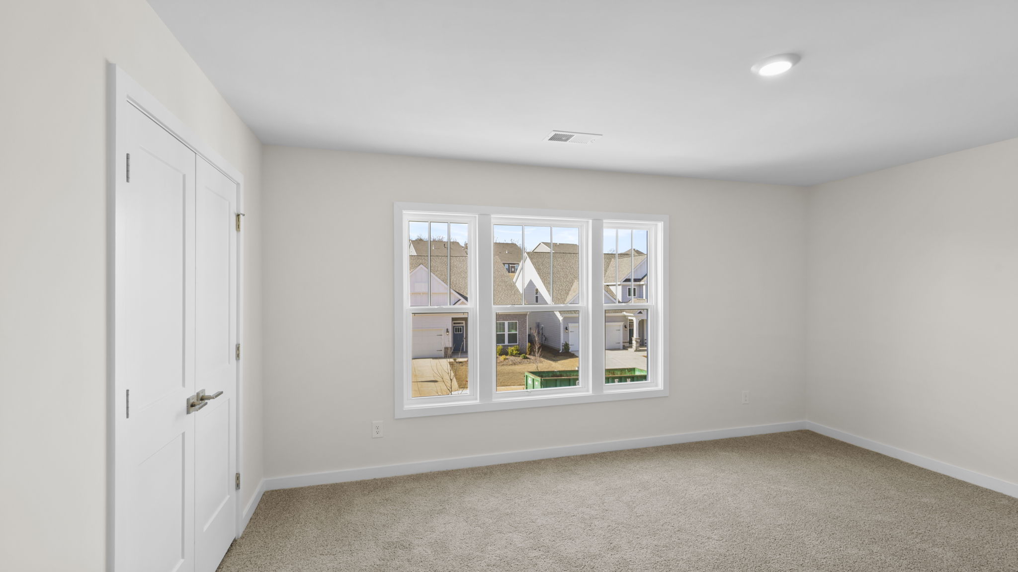 Bedroom with large windows and carpet.