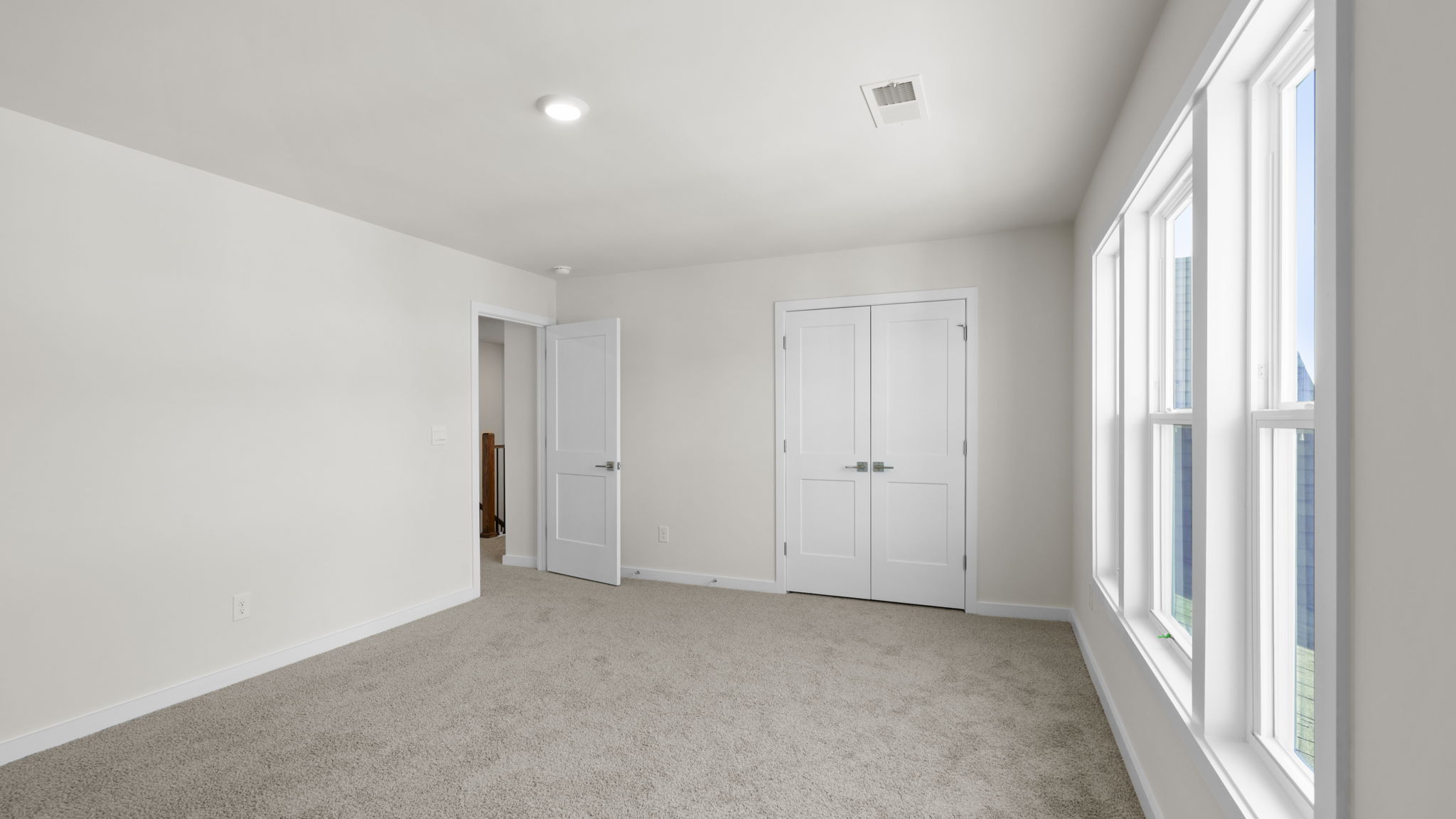 Bedroom with large windows and carpet.