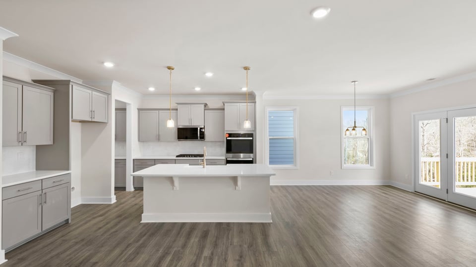 View of kitchen island, gas stovetop, microwave, open to the adjoining informal dining area, and great room.