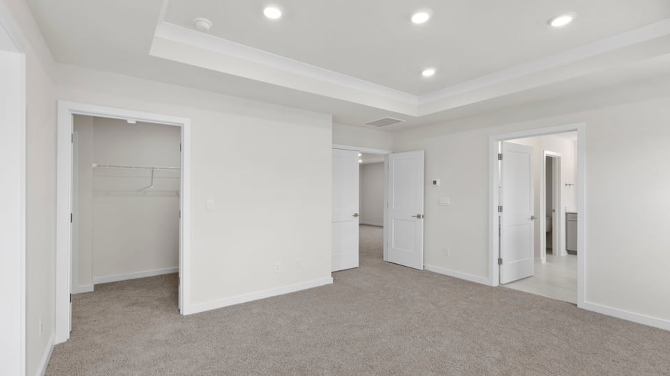 View of primary bedroom with trey ceiling, recessed lighting and entrance to the bathroom.