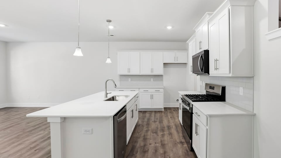 Kitchen and island with quartz countertops and stainless steel appliances.